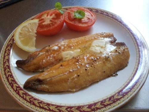 a plate of food with fish and tomatoes on a table at The Collingdale Guest House in Ilfracombe