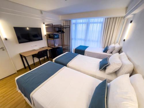 a hotel room with two beds and a desk at Marante Plaza Hotel in Recife