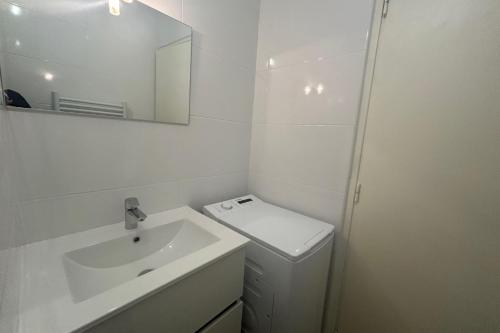 une salle de bain blanche avec un lavabo et un miroir dans l'établissement 2 rooms with your feet in the water, à Frontignan