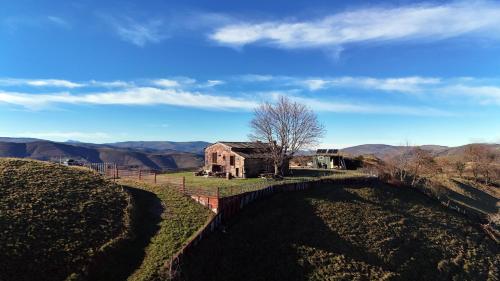 an old house on a hill with a fence at La cabaña mirador de los Valles Pasiegos in Vega de Pas