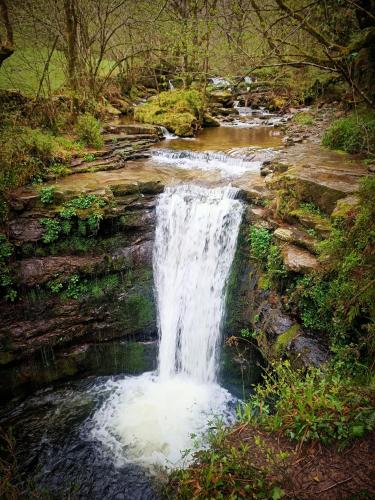 a waterfall in the middle of a river at La cabaña mirador de los Valles Pasiegos in Vega de Pas
