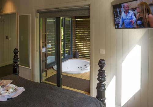 a bedroom with a tub and a tv in a bathroom at Broadoaks Boutique Country House in Windermere