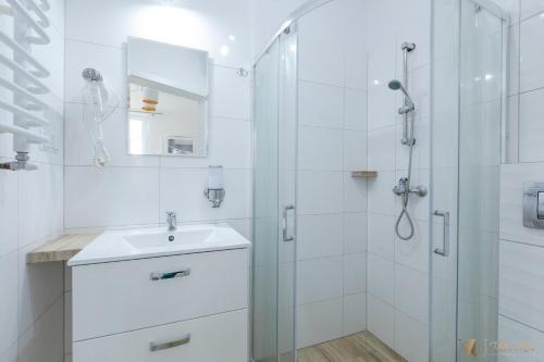 a white bathroom with a sink and a shower at Villa Ula in Pobierowo