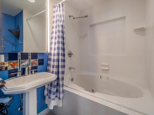 a bathroom with a sink and a tub and a shower at A Charm of Finches in Surf City