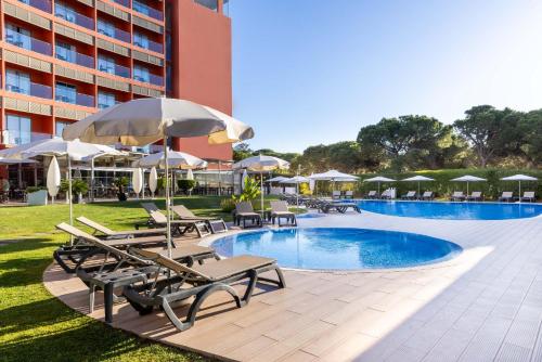 una piscina en un hotel con sillas y sombrillas en Aqua Pedra Dos Bicos Design Beach Hotel - Adults Friendly, en Albufeira
