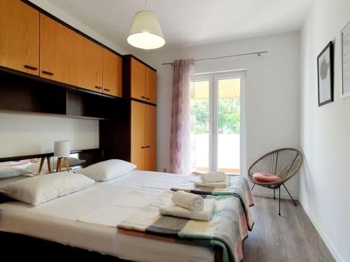 a bedroom with a large white bed with a chair at Apartman Sanja in Kostrena