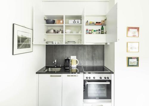 een witte keuken met een wastafel en een fornuis bij AM3Office apartment with contactless check-in near lake in La Tour-de-Peilz