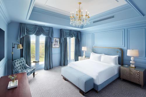 ein blaues Schlafzimmer mit einem Bett und einem Kronleuchter in der Unterkunft Nemacolin in Farmington