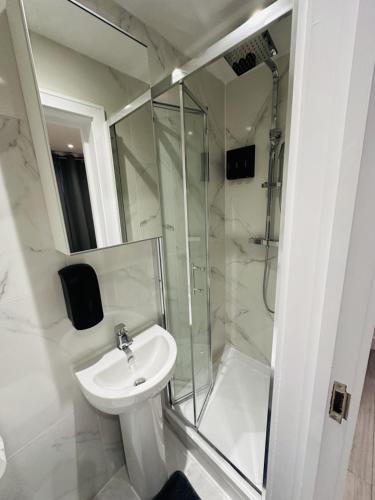 a white bathroom with a sink and a shower at Studio in Oval London in Bellaghy