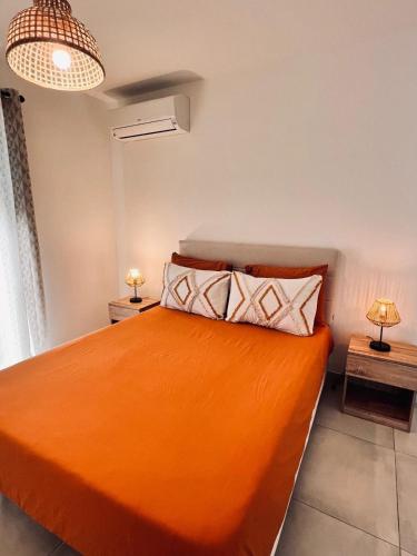 - une chambre avec un lit orange et deux lampes dans l'établissement Les jardins du Soleil, à Gorbio