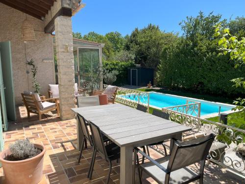 un patio avec une table et des chaises à côté d'une piscine dans l'établissement Villa avec Piscine et terrain de pétanque proche Avignon, à Rognonas