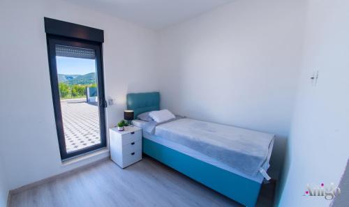 a bedroom with a blue bed and a window at Villa Elysian Blagaj in Blagaj