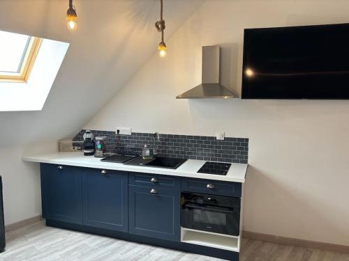 La cuisine est équipée de placards bleus et d'un four avec plaques de cuisson. dans l'établissement Nuit détente, à Saint-Christophe-en-Brionnais