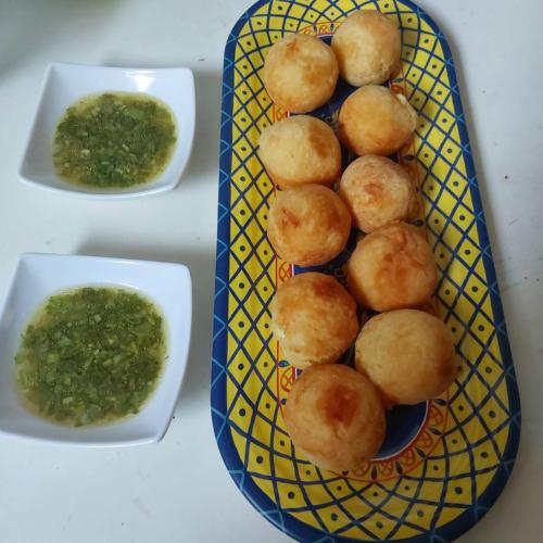a plate of food with green dipping sauce and rolls at Acuarela del Mar in Dibulla