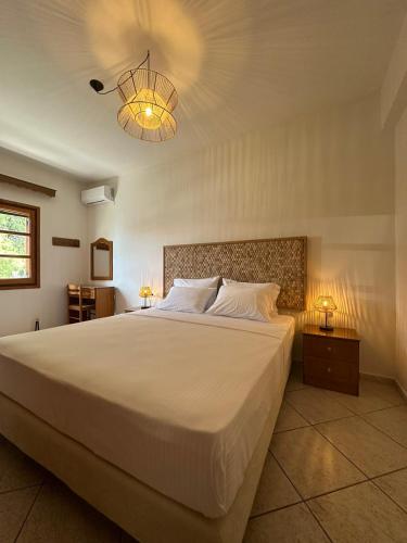 a bedroom with a large white bed and a chandelier at Kavos Apartments Alonissos in Patitiri