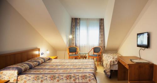 une chambre d'hôtel avec un lit, une table et des chaises dans l'établissement Hotel Caracas, à Lignano Sabbiadoro