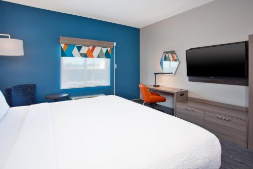 a hotel room with a white bed and a flat screen tv at Holiday Inn Express Augusta North by IHG in Augusta