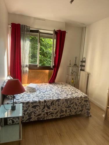 une chambre avec un lit et une fenêtre avec des rideaux rouges dans l'établissement Calm and Comfortable parisian studio, à Paris