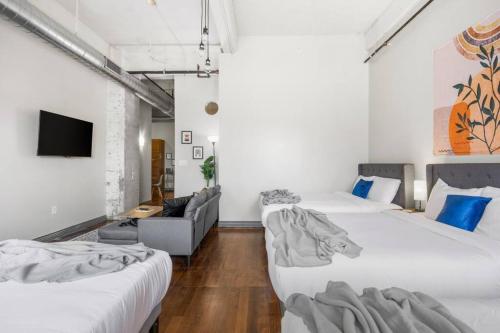 two beds in a room with a couch and a tv at Stunning Downtown Apartment with Pool, Laundry, Parking in Dallas
