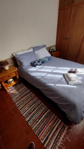 a bedroom with a bed with a blue comforter and a table at Casa do Granel in Sete Cidades