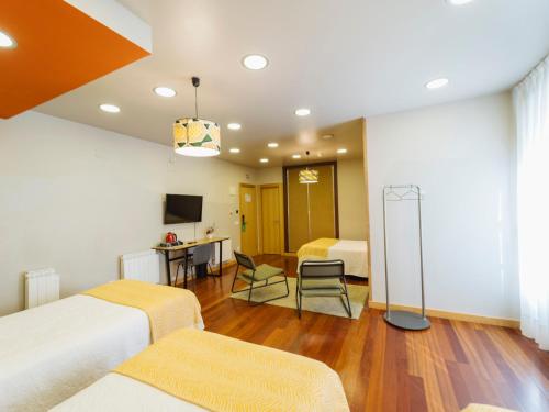 a hotel room with two beds and a desk at Hotel San Miguel in Gijón