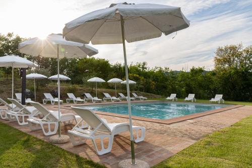 a pool with a bunch of chairs and umbrellas at Relais Parco Del Subasio in Piano Delle Pieve