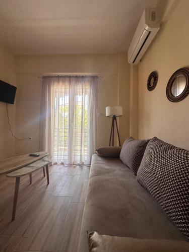 a living room with a couch and a window at Elinor Pefkochori in Pefkohori