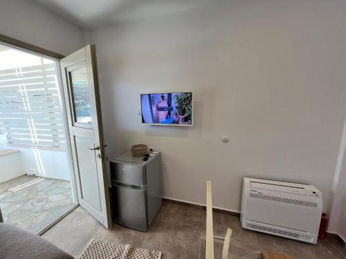 um quarto com um frigorífico e uma televisão na parede em Captain's Port Studio em Gavrio