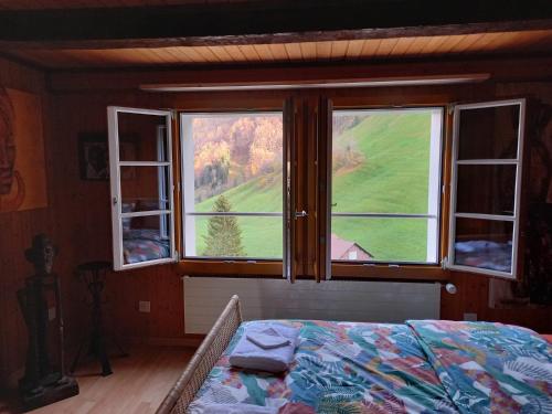 a bedroom with a bed and two windows with a view at Afrika Zimmer mit Bergblick in Emmetten