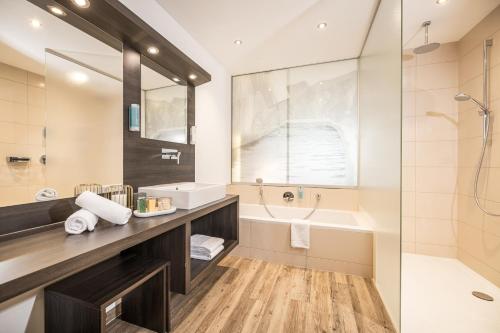 een badkamer met een bad, een wastafel en een douche bij zum Senner Suites Zillertal in Schlitters