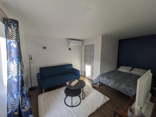 une chambre avec un canapé bleu et un lit dans l'établissement appartement climatisé Aubenas, à Aubenas