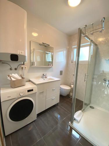 a bathroom with a sink and a washing machine at Apartmani Villa Adriatic in Vir