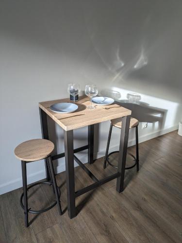 - une table en bois avec deux verres à vin et deux tabourets dans l'établissement appartement climatisé Aubenas, à Aubenas