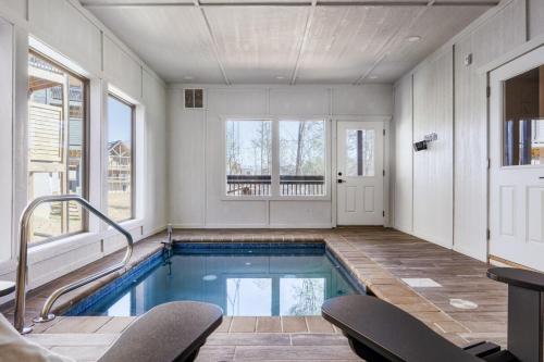 a swimming pool with two chairs in a large room at Private Indoor Pool Cabin w/ Game Room & Hot Tub! in Pigeon Forge