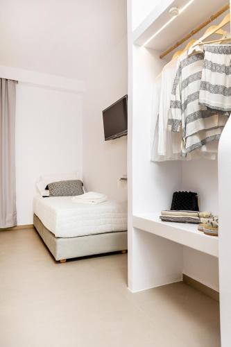 a white bedroom with a bed and a tv at Alenor City Hotel in Naxos Chora