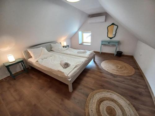 a bedroom with a bed with white sheets and wooden floors at Szarvas és Bagoly Kalandház in Szarvas