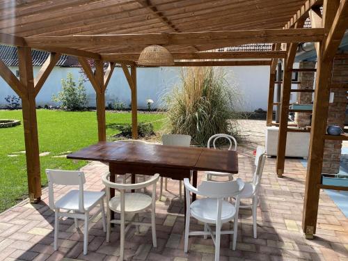 a wooden table and chairs under a pergola at Szarvas és Bagoly Kalandház in Szarvas