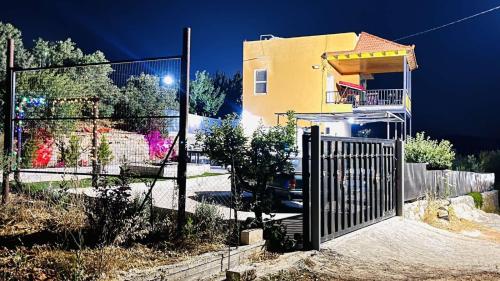 einen Zaun vor einem gelben Haus in der Unterkunft Mustafa Farm in Adschlun