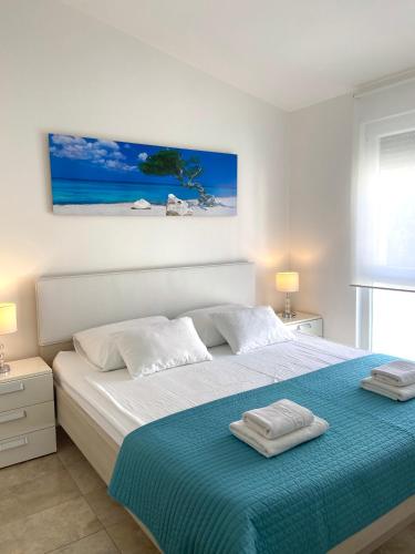 a white bedroom with a bed with a blue blanket at Apartmani Villa Adriatic in Vir