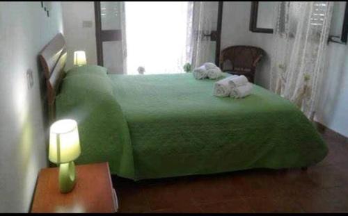 a bedroom with a green bed with towels on it at Villa paradiso in Castellammare del Golfo