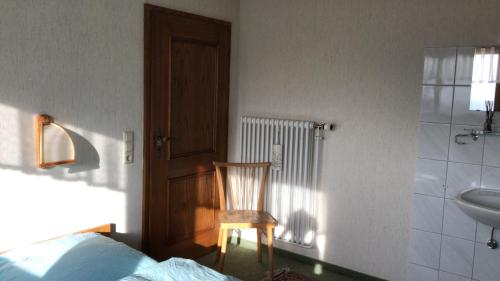1 dormitorio con silla, 1 cama y lavamanos en Haus Imgard en Lenzkirch