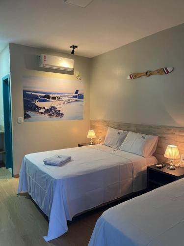 a bedroom with two beds and two lamps and a painting at Voar Pousada in Barreirinhas