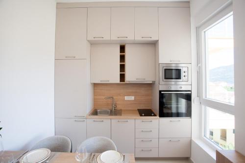 a kitchen with white cabinets and a table with chairs at Boka Panoramic in Đenovići