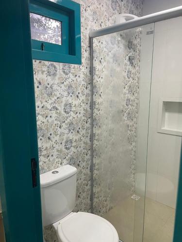 a bathroom with a toilet and a glass shower at Voar Pousada in Barreirinhas