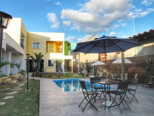 a patio with a table with an umbrella and a pool at Pousada Sr. Ivan in Serra do Cipo
