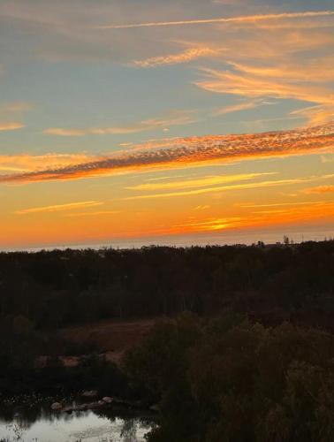 a sunset over a field with trees and a river at Zen and cosy Appart Rose Marie Kasbah in Skhirat