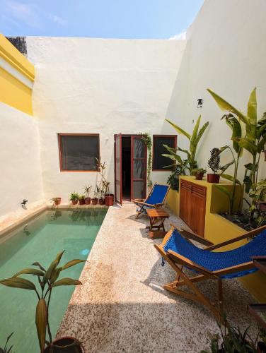 a courtyard with a pool and chairs and a house at Casa Mi María in Campeche