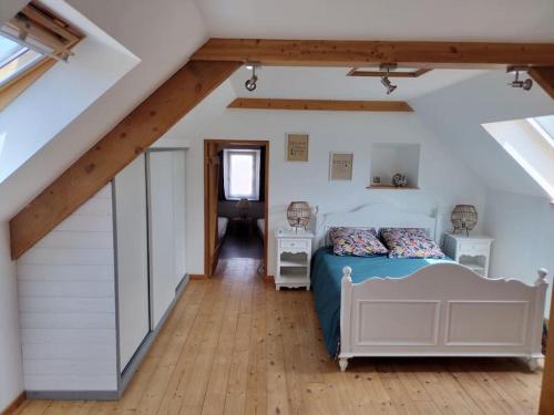 une chambre avec un lit dans un grenier dans l'établissement Maison de pays à Vicq-sur-mer, à Cosqueville