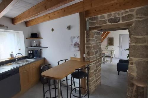 une cuisine avec un comptoir et un mur en pierre dans l'établissement Maison de pays à Vicq-sur-mer, à Cosqueville