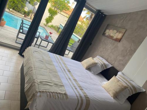 a bedroom with a large bed with a view of a pool at Teresa Beauté - grande maison 4 chambres proche La Rochelle Ile de Ré avec piscine in Périgny